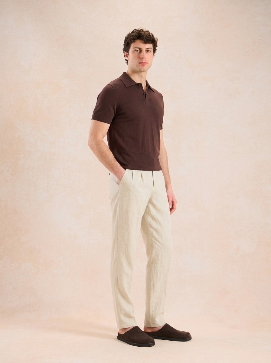 AI-generated model wearing a brown polo and cream trousers against a warm textured backdrop